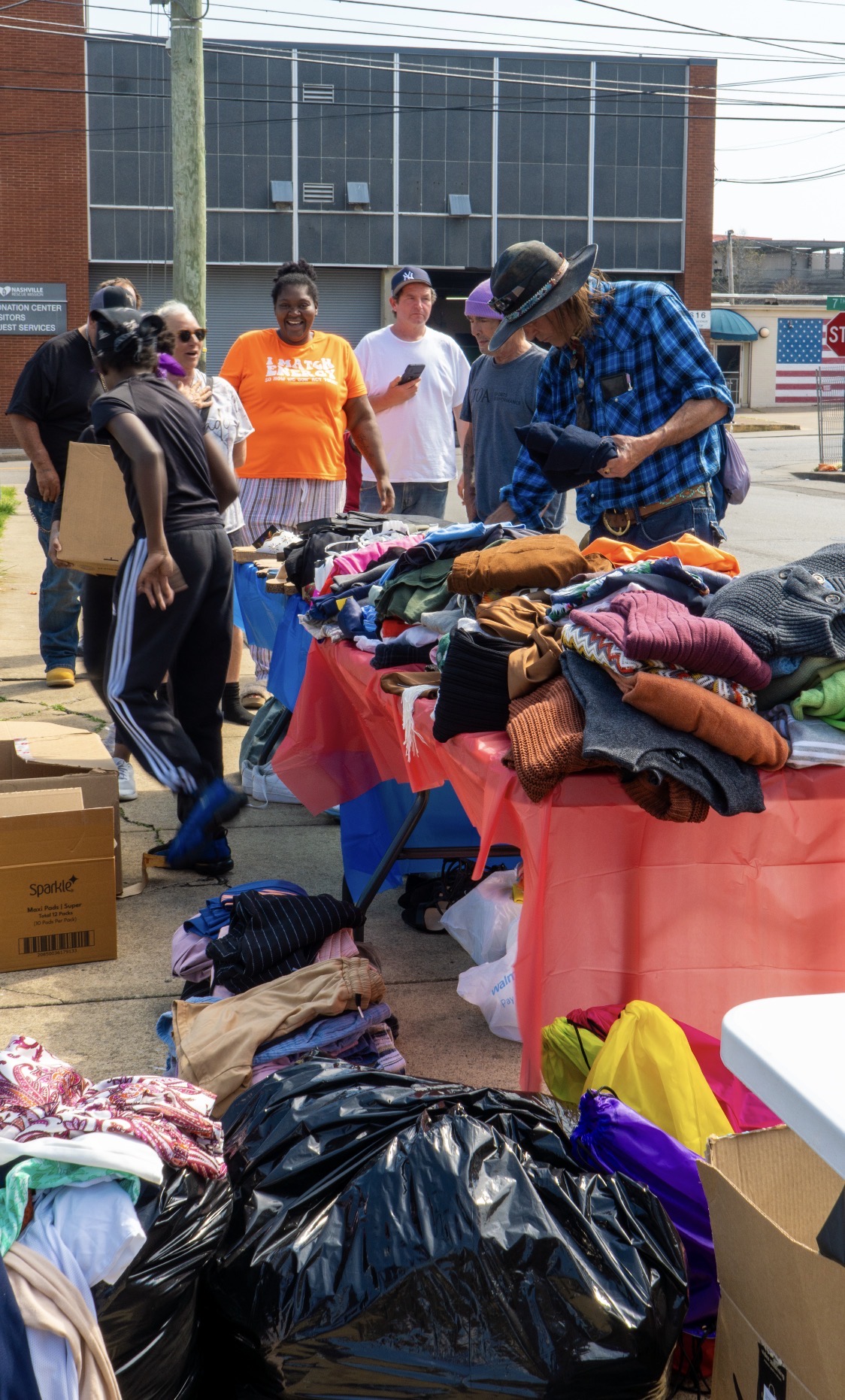 Neighbors browsing free clothing at a Harvest Her outreach table